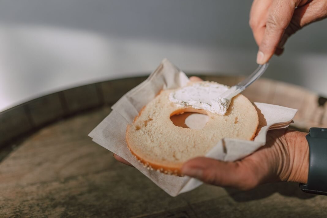 Best bagels in Queens - fresh bagel getting cream cheese spread on top
