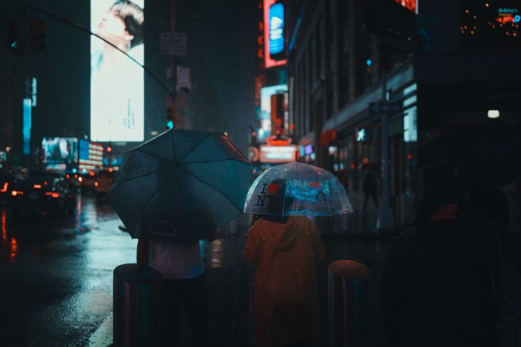 Rainy day activities NYC — people with umbrellas on a rainy Times Square street at night