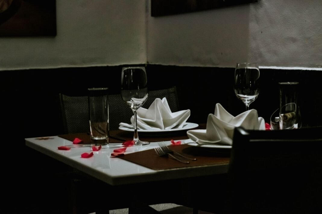 Anniversary dinner nyc — candlelit restaurant table set for two with wine glasses
