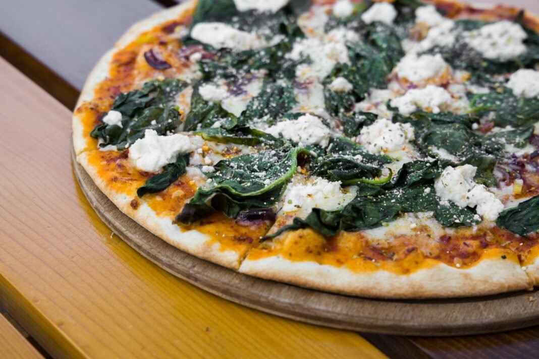 Best vegan NYC pizza: vegetarian pizza with spinach on a wooden board